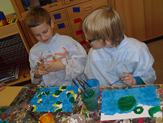 Zwei Kinder malen Bilder mit Tusche